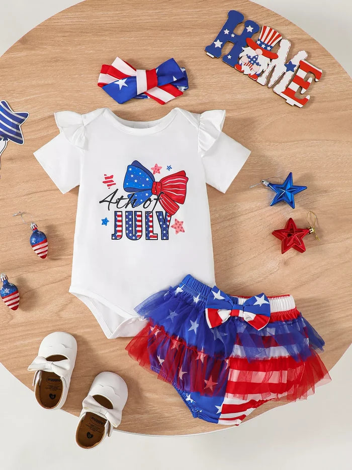 Children's outfit with '4th of July' design on a wooden surface with decorative items.