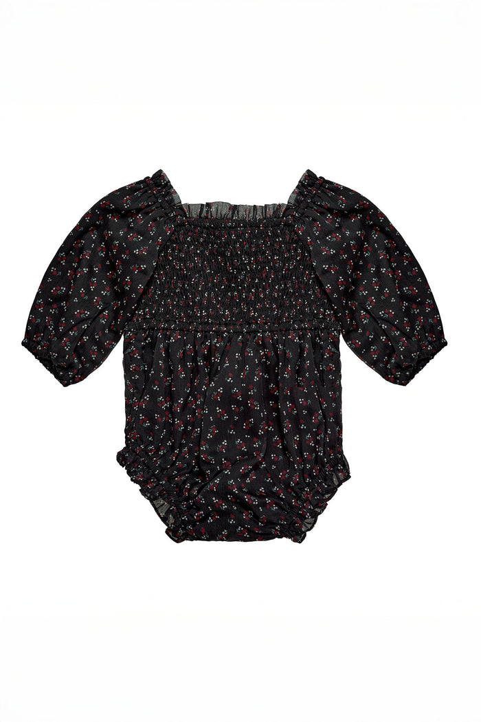 The Ivy City Co Baby Madeline Romper in Black Ditsy Floral features a delicate red and white ditsy print, puffed half-sleeves, a smocked bodice, and ruffled elastic leg openings, beautifully laid flat on a white background.