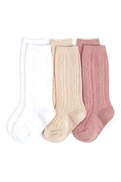 The Ivy City Co Cable Knit Knee High Sock 3-Pack features white, beige, and dusty pink socks for kids—ideal for pairing with baby dresses or ruffle-trim outfits.