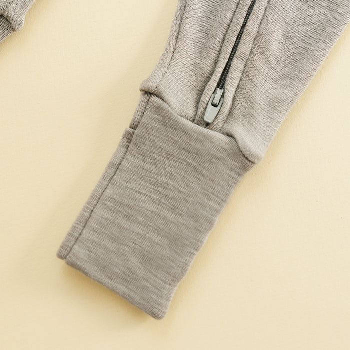 Dove color footless baby romper zipper close-up on a beige surface