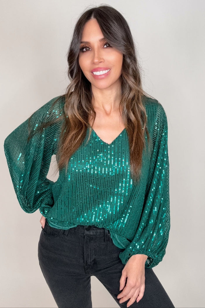 Hunter green V-neck sequin blouse top with allover sparkle, balloon sleeves, and elasticized cuffs.
