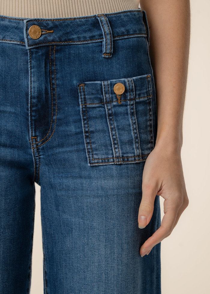 Close up of a woman wearing dark blue wide leg jeans with a tan tank top