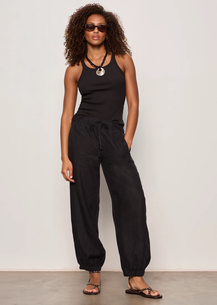 Woman wearing black linen joggers with a black tank top and sandals