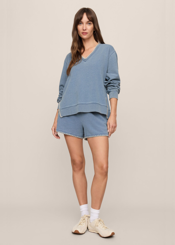 Woman wearing a blue knit denim sweatshirt with whipstitch trim and matching shorts