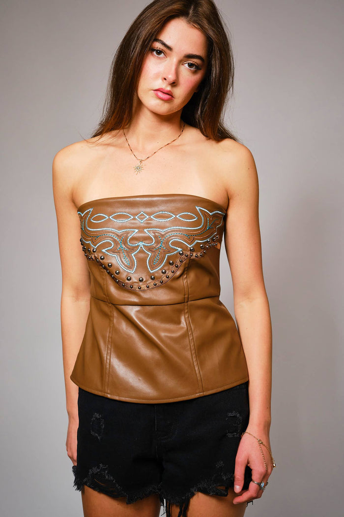 Brown faux leather strapless tube top with turquoise Western embroidery, antique-style stud trim, and a softly flared hem.