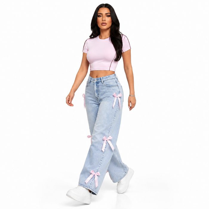 Women's bowknot jeans in light blue washed denim with pink ribbon details, shown in a walking studio pose