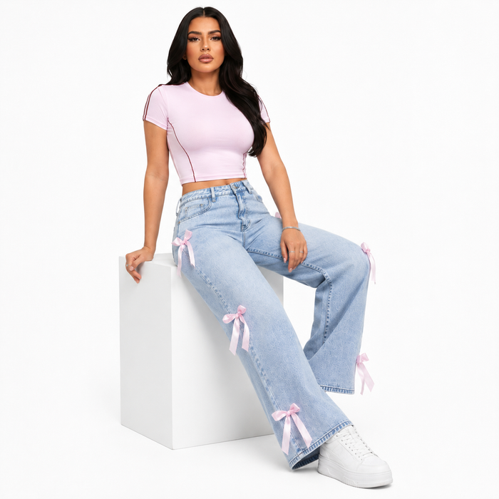 Women's light blue bowknot jeans with pink ribbon accents in a seated studio pose on a clean white background