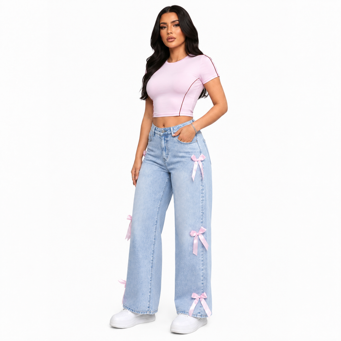Light blue washed women's bowknot jeans with pink ribbon accents, side studio view highlighting the outer leg details
