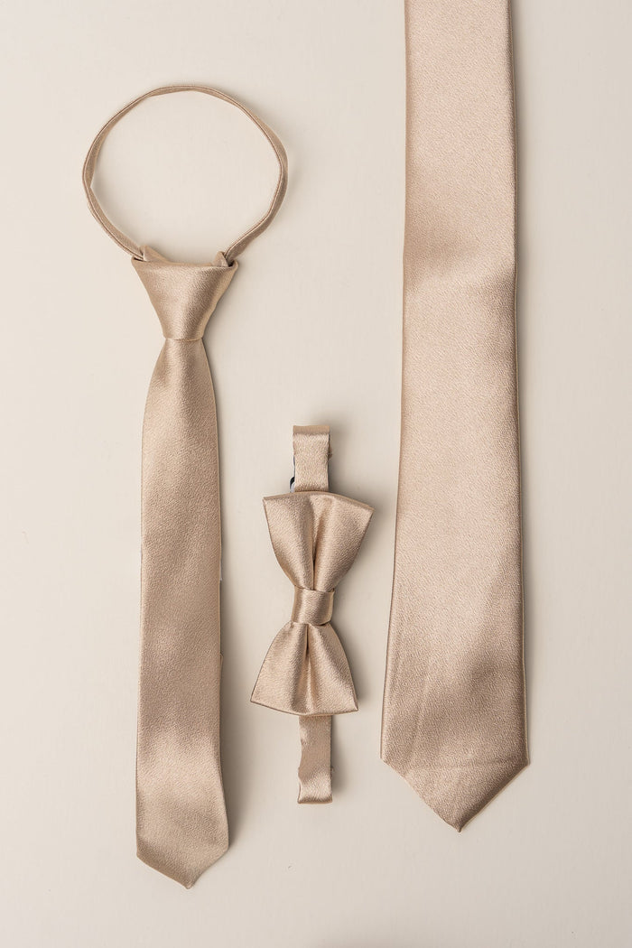 Three beige satin neck accessories—a champagne tie, an Ivy City Co pre-tied bow tie with adjustable strap, and the Boys Max Tie in Champagne—are arranged vertically on a light background, making them perfect wedding accessories.