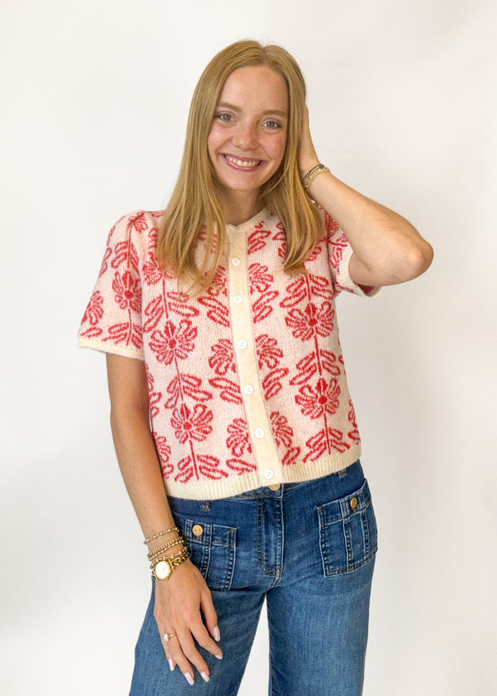 Woman wearing a short sleeve red and cream floral button down cardigan
