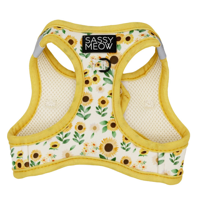 The Cat Step-In Harness - Sunflower Dreams by Sassy Woof features yellow edges, a leafy sunflower design on white fabric, reflective strips for safety, a black Sassy Woof label, and a metal ring for attaching a leash.
