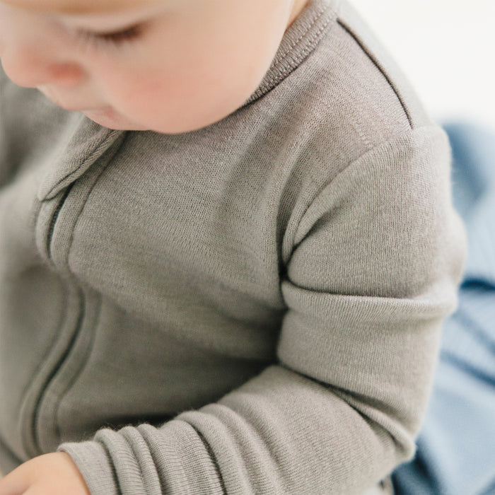 Close-up of a baby wearing a Dove color footless baby romper.
