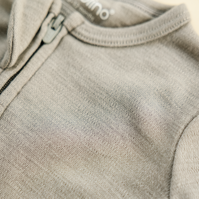 Close-up of a Dove color footless baby romper with a brand logo on the collar.
