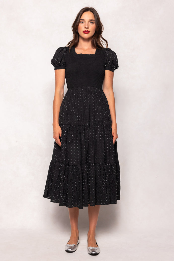 Woman wearing a black dress with white polka dots on a white background