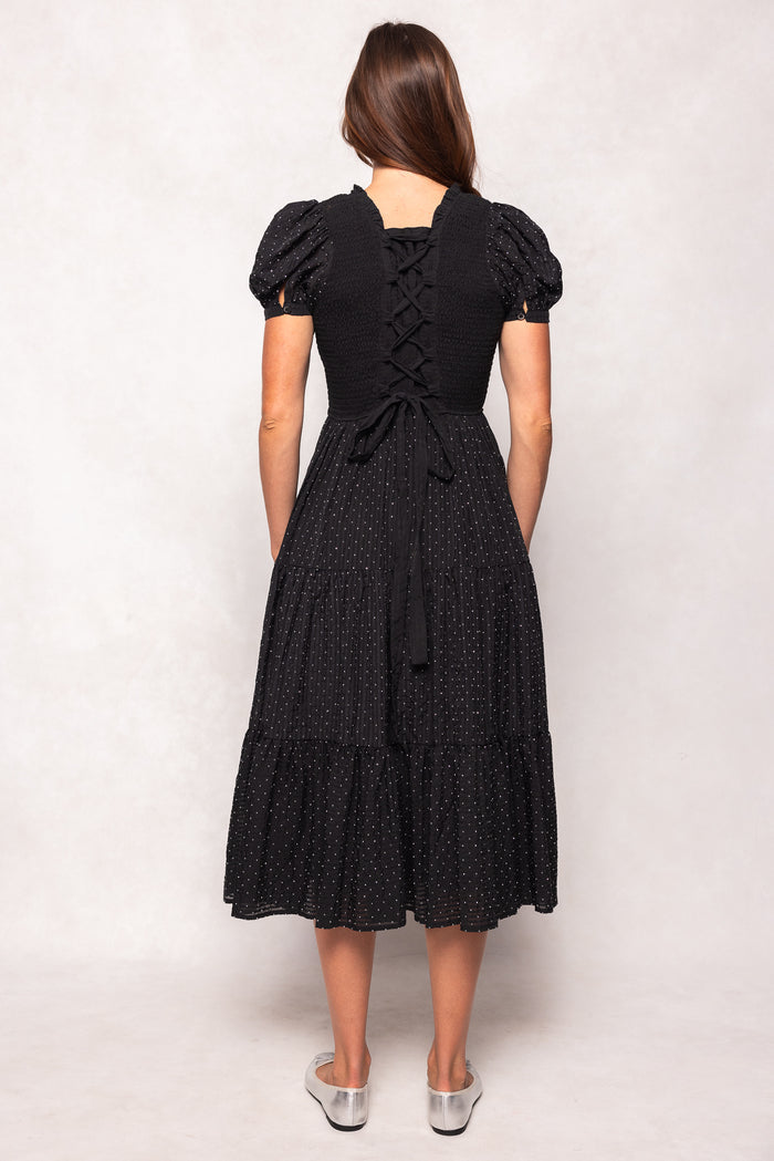 Woman wearing a black dress with white polka dots on a white background