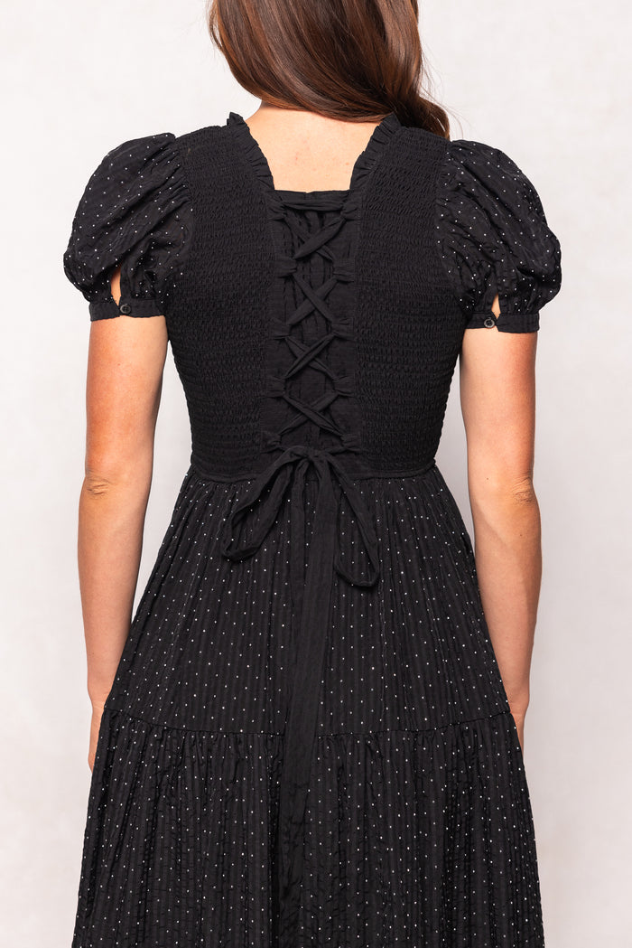 Black dress with puff sleeves and lace-up back on a plain background