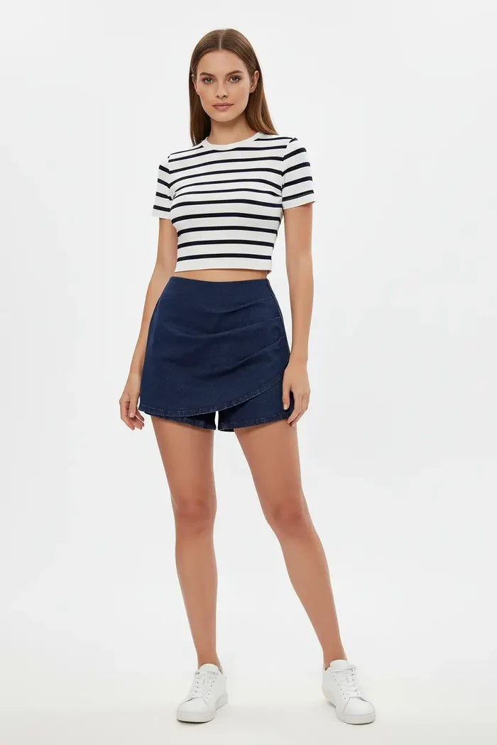 high waisted stretch denim shorts light blue color close up on pleated front detail and high rise waistband showing refined tailoring and moderate stretch comfort perfect for active elegant lifestyle during beach outing with ocean breeze visible
