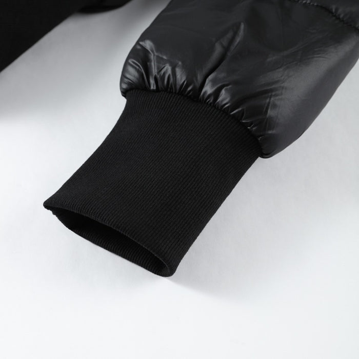 Close-up of a black quilted jacket sleeve on a white background