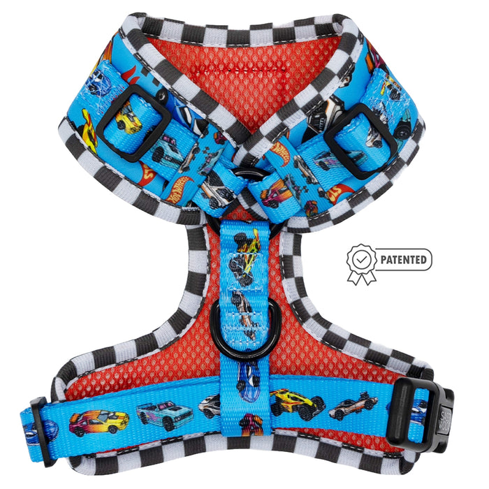 The Sassy Woof Dog Adjustable Harness – Hot Wheels™ features a blue base with race cars, checkered trim, black buckles, metal rings, a red mesh lining, and patented badge. Includes the Puppy Growth Pawtection Plan for peace of mind.