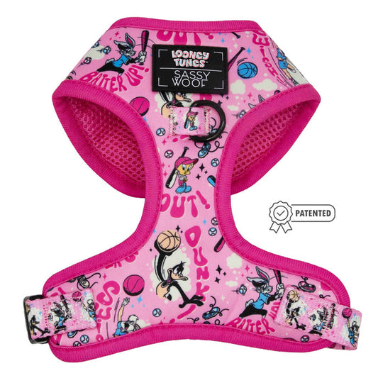 The Dog Adjustable Harness - Looney Tunes™ Pink by Sassy Woof features vibrant cartoon designs, basketballs, and stars, plus a “Patented” badge and buckle. This adjustable harness is perfect for playful pups.