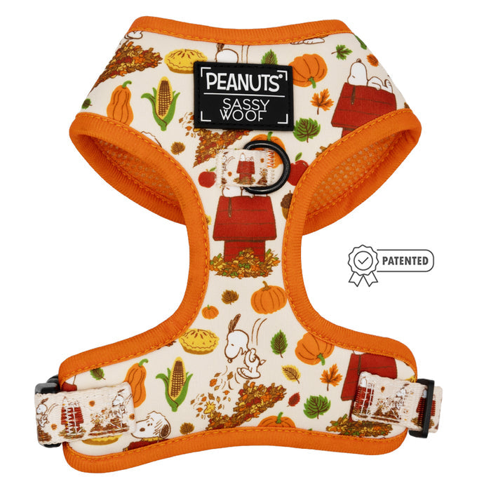 The Dog Adjustable Harness - Peanuts™ Harvest by Sassy Woof features autumn leaves, pumpkins, classic Peanuts characters, a PEANUTS SASSY WOOF label, patented symbol, and a no pull design—perfect for fall outings.
