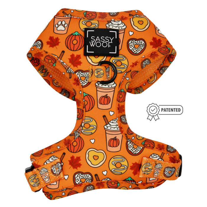 The Dog Adjustable Harness - Pupkin Donuts by Sassy Woof features autumn-themed prints—pumpkins, coffee cups, leaves, donuts, pretzels, and paw prints—black buckles, a patented badge, and supports the Puppy Growth Pawtection Plan.