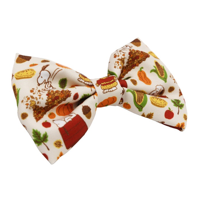 The Sassy Woof Dog Bowtie - Peanuts™ Harvest features a cream base with colorful Thanksgiving icons like turkey, pie, pumpkins, and leaves—a delightful accessory for Snoopy fans and stylish pups alike.