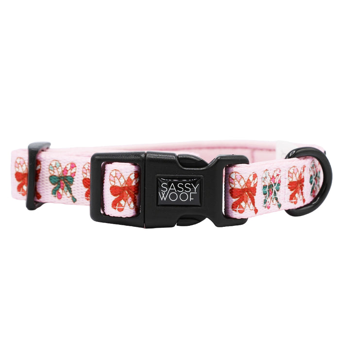 The Sassy Woof Dog Collar - Candy Cane Coquette features pink adjustable webbing, a black plastic buckle, and festive holiday design—an ideal addition to your collection of charming dog accessories.