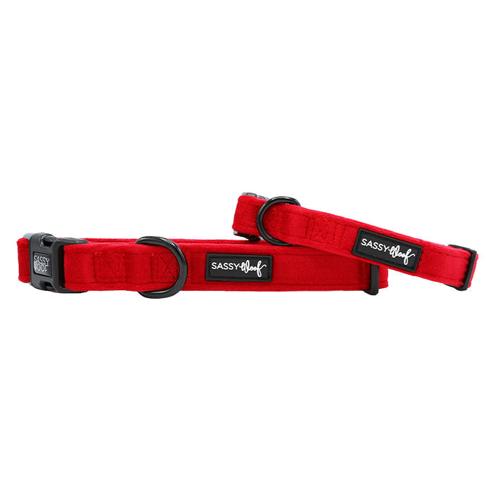 Two bright red “Dog Collar - Naughty” velvet collars by Sassy Woof with black hardware, quick-release buckles, and adjustment sliders are displayed against a white background.