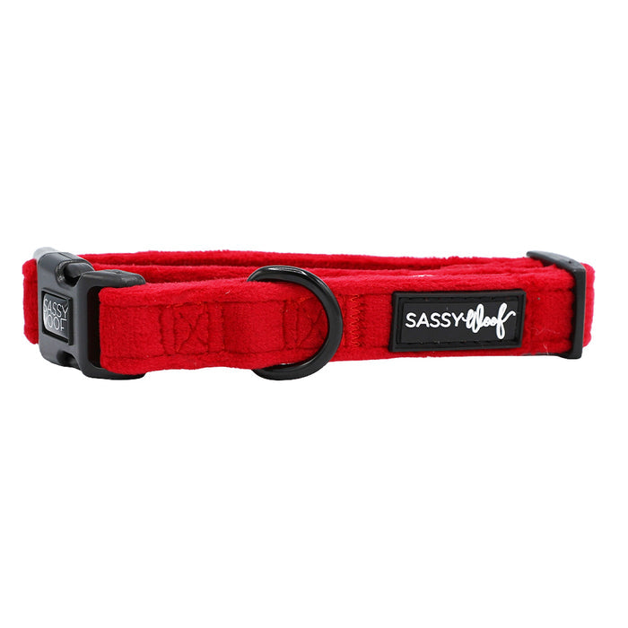 The "Naughty" Dog Collar by Sassy Woof features bright red velvet, black hardware, a plastic buckle, a D-ring, and a black label with white "SASSY WOOF" text—ideal for adding holiday flair to your pup's accessories.