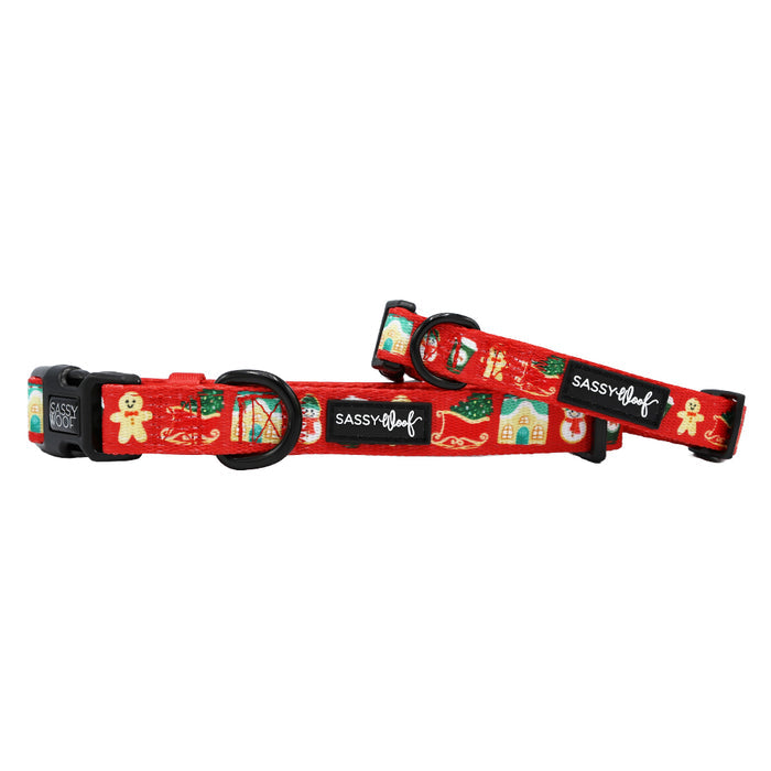 Two Sassy Woof 'Sleigh Baby Sleigh' red adjustable dog collars with black buckles and metal rings, featuring festive gingerbread men, candy canes, and houses—perfect holiday accessories for your pup.