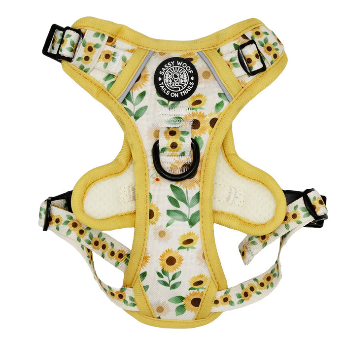 The Sassy Woof Dog Step-In Harness – Sunflower Dreams features a yellow and white sunflower pattern, reflective straps, black buckles, and a circular black-and-white "Sassy Woof Tails on Trails" label on the chest.