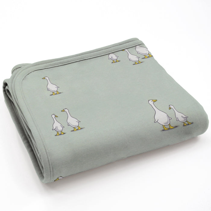 Folded light green blanket with duck illustrations on a white background