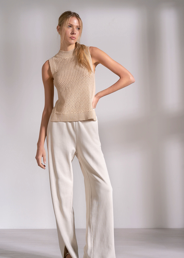 Woman wearing a tan knit tank top with cream pants