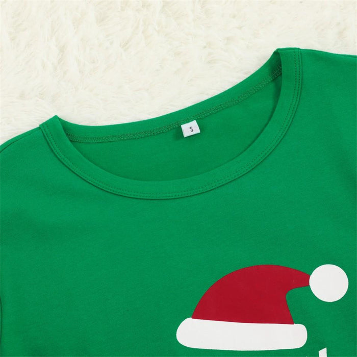 Family in green matching Christmas pajamas enjoying a cozy holiday movie night
