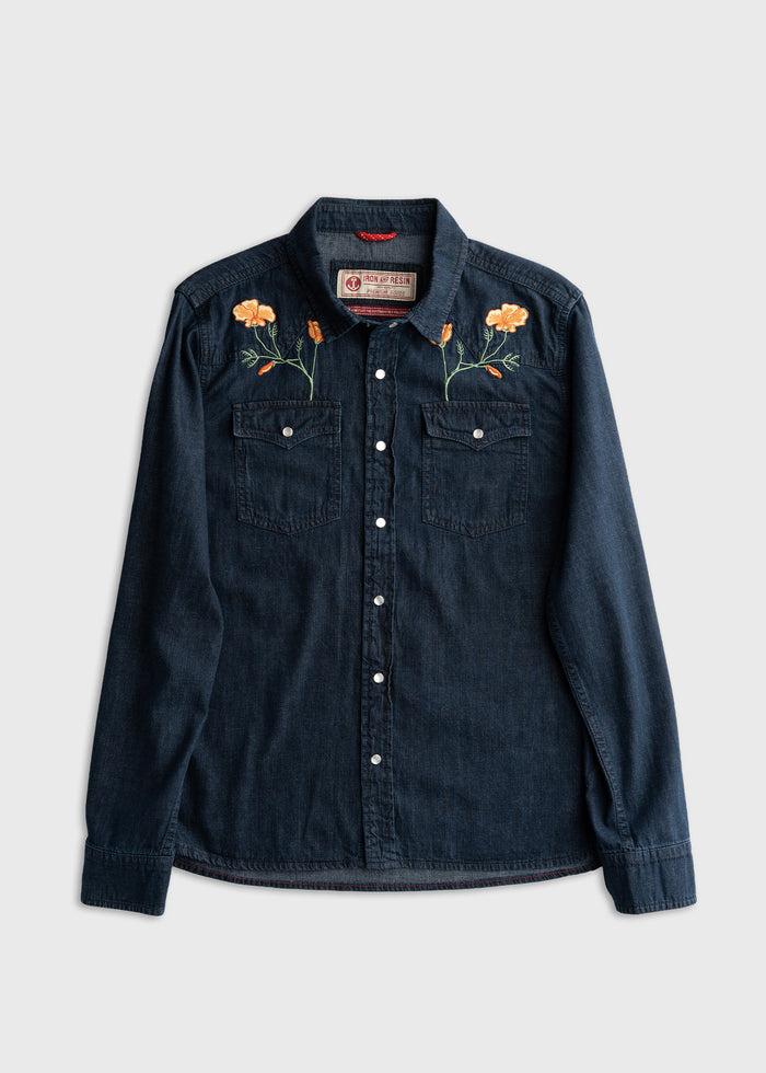 Denim shirt with floral embroidery on shoulders, featuring two chest pockets and button closure, displayed on a plain background.