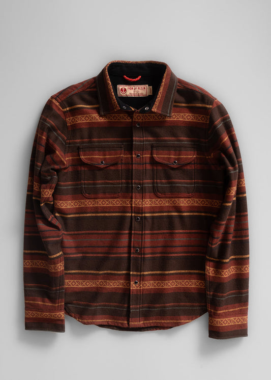 Brown and orange striped flannel shirt with button-up front and two chest pockets, displayed on a light gray background.