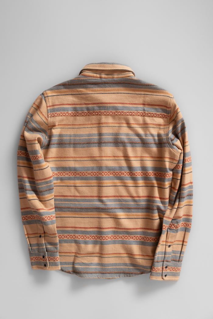 A beige and gray striped flannel shirt with buttoned cuffs is laid flat on a plain background, showcasing its back design.