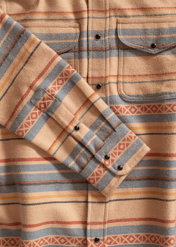 Tan shirt with blue, red, and yellow stripes, featuring geometric patterns and black buttons. Two chest pockets are visible.