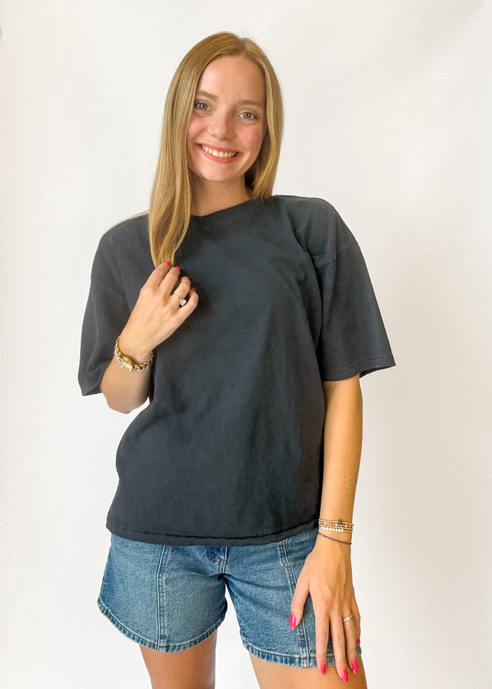Woman wearing a black t-shirt and denim shorts against a white background