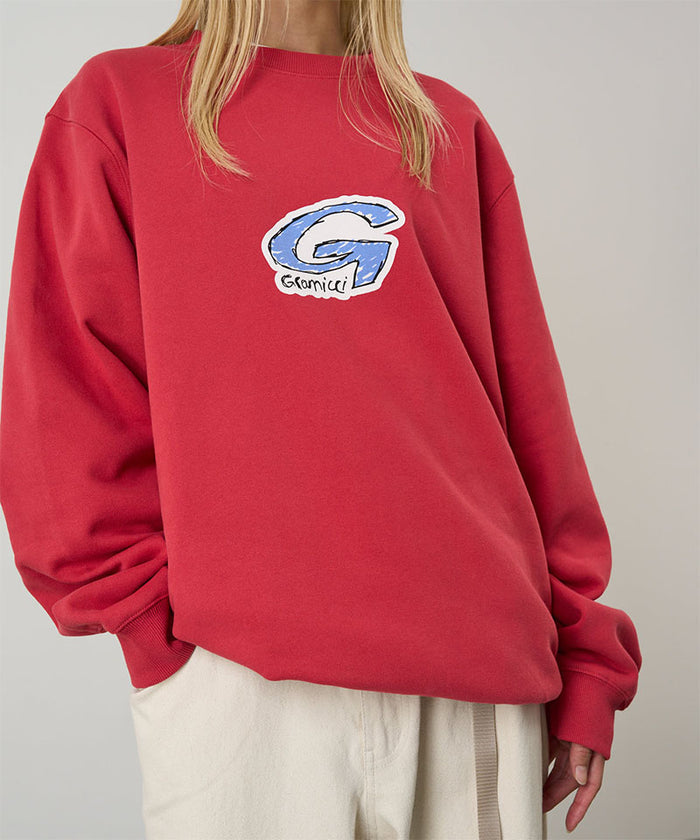 Model wearing a Gramicci crimson red G-Scribble Sweatshirt with blue graphic against a light tone background.