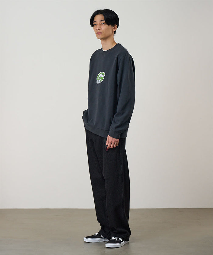 Model wearing a vintage black Gramicci G-Scribble Sweatshirt with a green graphic and black pants on a light tone background.