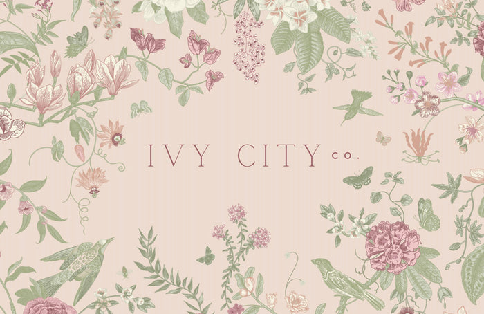 A pastel pink Ivy City Co Gift Card ($10-$250) features the brand name framed by floral, leaf, butterfly, and bird illustrations in soft pink and green tones—making it a dreamy gift.