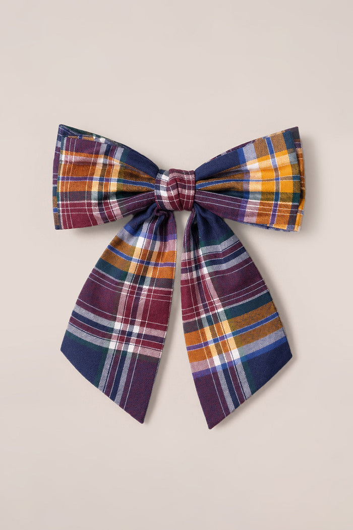 Ivy City Co’s Hair Bows in Midnight Plaid feature wide loops and long tails in maroon, yellow, navy blue, and white striped fabric—set against a plain beige background for a charming accessory.