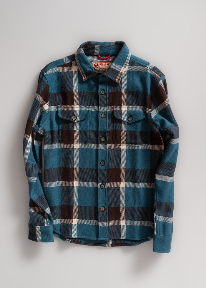 Blue and brown plaid flannel shirt with buttoned front and two chest pockets, displayed against a plain gray background.