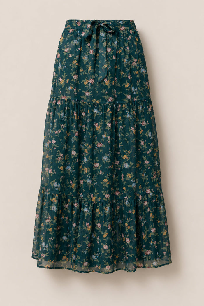 Introducing the Imogen Skirt in Evergreen Elysian Vine by Ivy City Co—a long, dark green skirt adorned with a delicate pattern of small pink, yellow, and green flowers. This flowy, tiered design features a drawstring waist and is crafted from lightweight chiffon fabric, making it the perfect airy addition to elevate your fall wardrobe.