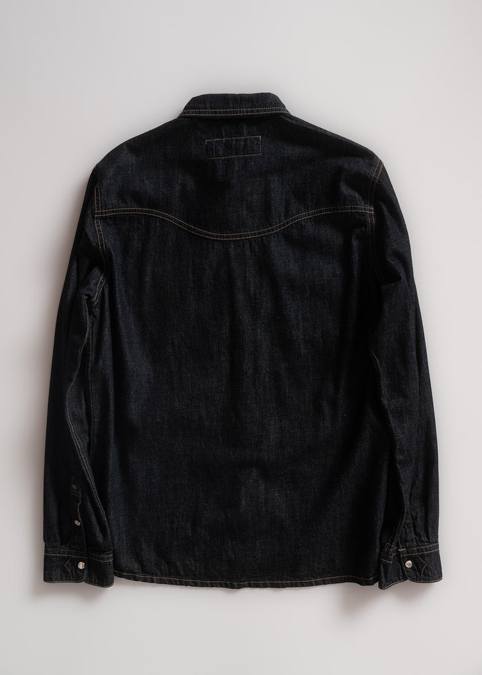 Back view of a dark denim jacket on a light background, showcasing stitching details and buttoned cuffs.