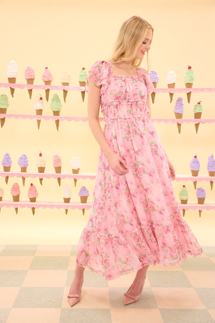 Woman in a pink floral dress standing in front of an ice cream cone display.