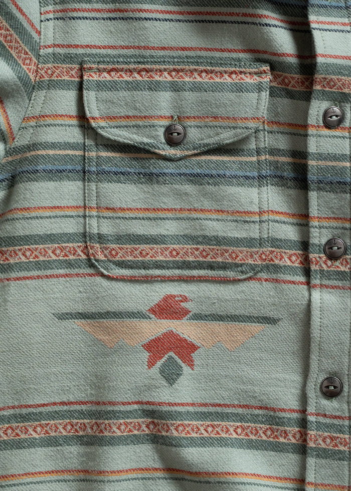 Green shirt with a pocket, featuring red and beige geometric patterns and stripes, buttoned up for a casual look.