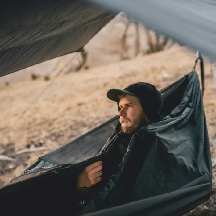 man laying inside a Lifesystems Expedition Mosquito Net Hammock outdoors with a tarp overhead